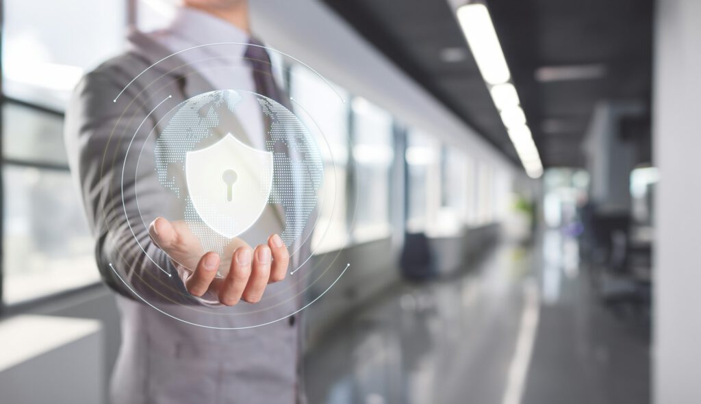 Businessman Presenting Cybersecurity Shield with Digital Interface in Office